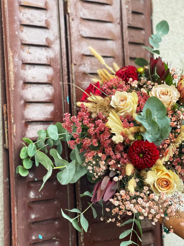 Un bouquet de fleurs dans les tons rouges et jaunes avec du feuillage vert