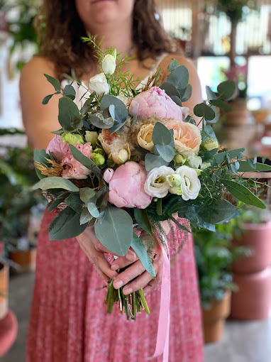 Un bouquet de fleurs pour une mariée composé de pivoines roses et eucalyptus, tenu par la fleuriste Pauline