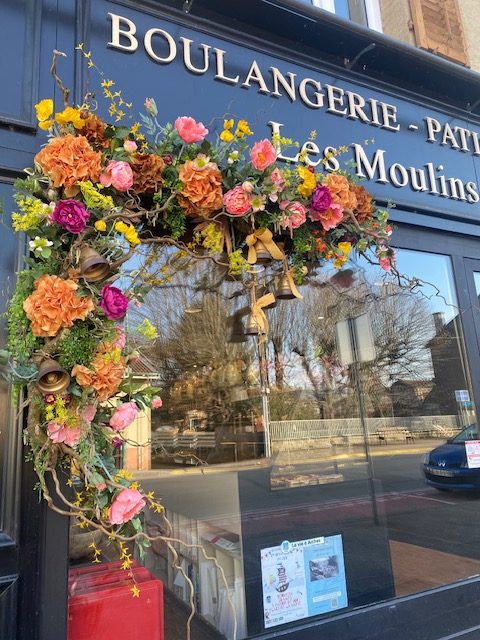 Photo d'une décoration florale dans les tons oranges et roses sur la vitrine d'une boulangerie