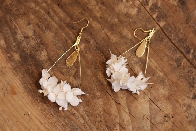De jolies boucles d'oreille dorées crées à la main avec de petites fleurs blanches séchées
