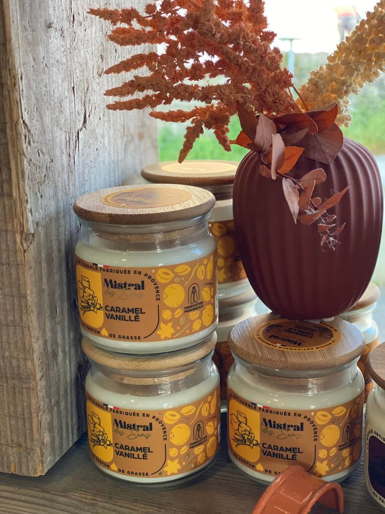 Les bougies artisanales Mistral des Sens au caramel et à la vanille posées à coté d'un vase de fleurs séchées