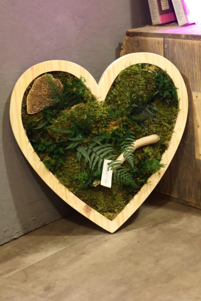 Un cadre végétal en forme de coeur, composé de fougère et de mousse