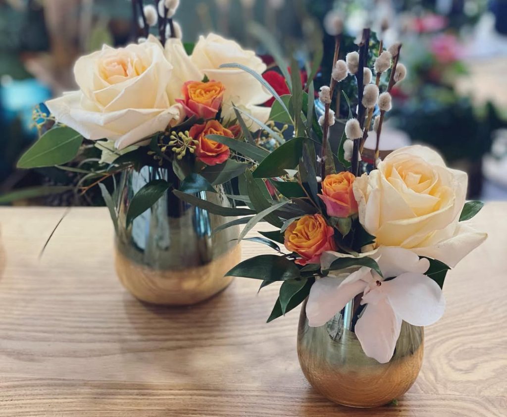 Deux compositions florales dans des petits vases avec des roses blanches et oranges pour décorer les tables pour un baptême à Arches