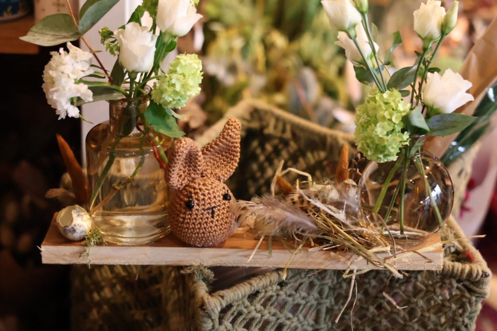 Une jolie composition réalisée pour Pâques avec des fleurs blanches, une petite peluche artisanale en forme de lapin et quelques plumes