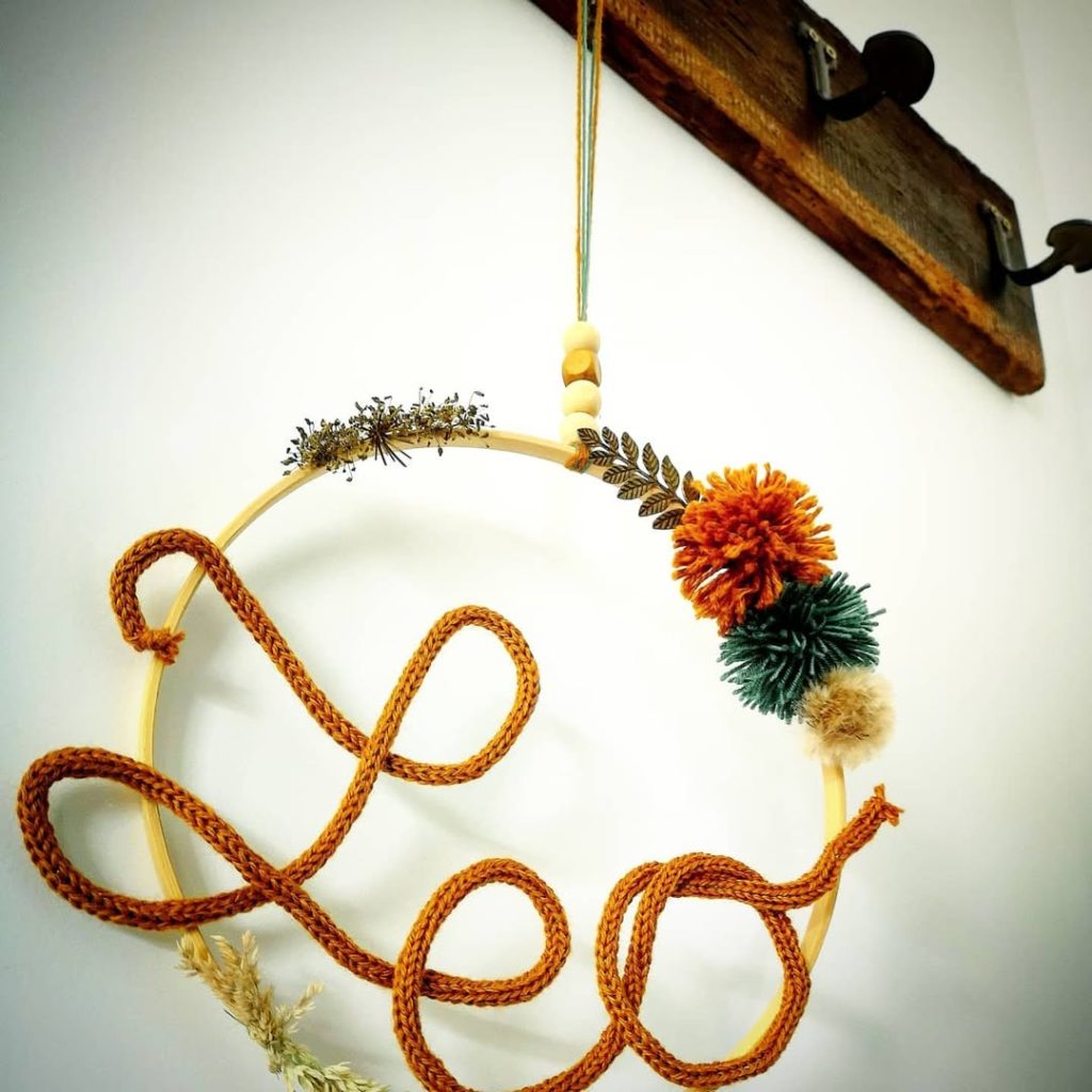 Couronne murale artisanale avec le prénom « Léo » formé en corde, décorée de fleurs séchées et pompons, crée pour une naissance à Arches