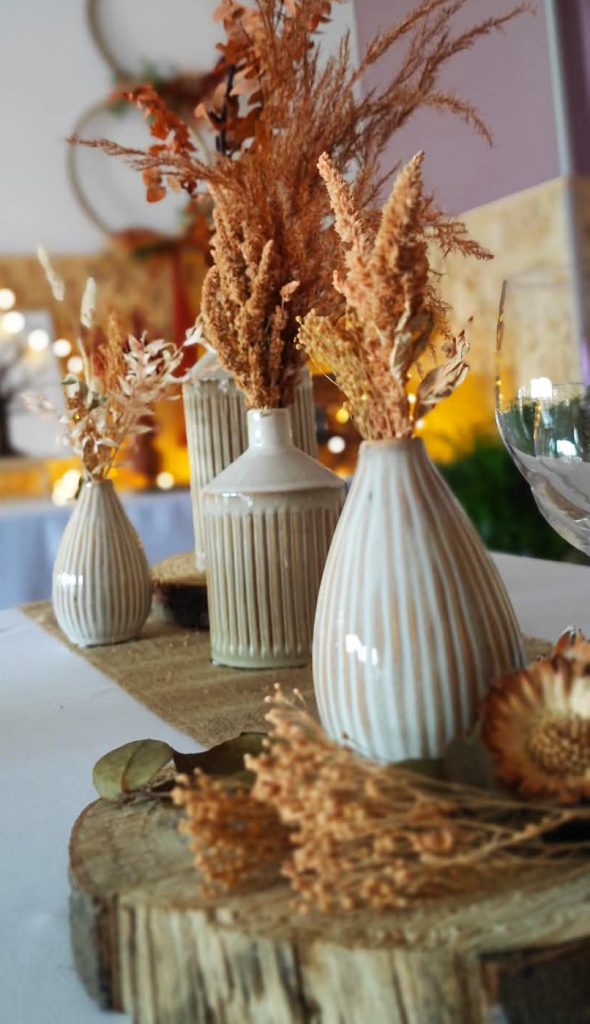 Des vases composés de fleurs séchées oranges sont placés au centre d'une table décorée pour un mariage dans les Vosges