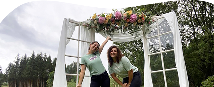 Les deux fleuristes Pauline et Sabrina sont sous une arche florale qu'elles ont réalisé pour un mariage