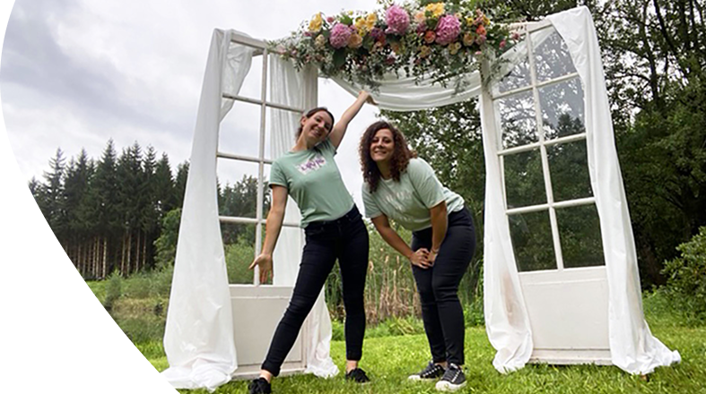 Les deux fleuristes Pauline et Sabrina sont sous une arche florale qu'elles ont réalisé pour un mariage