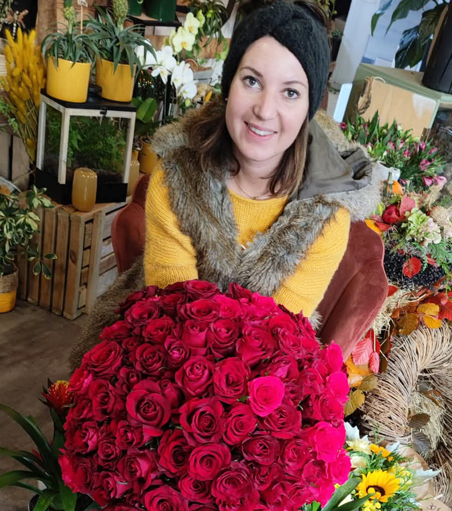 Photo de la Fleuriste Un Brin d'Folie à Arches qui sourit et tient dans ses mains un magnifique bouquet de roses rouges