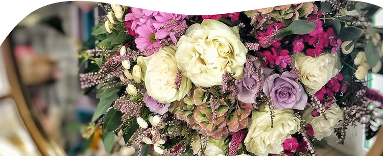 Un bouquet de fleurs placé devant un miroir, dans les tons roses, violets et blanc