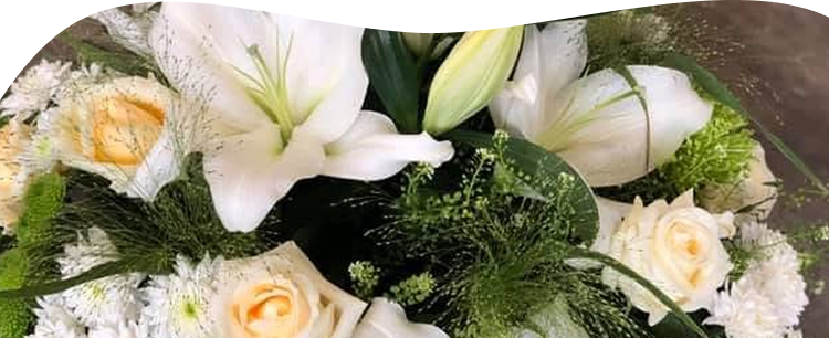 Une composition florale funéraire avec des fleurs de lys blanches