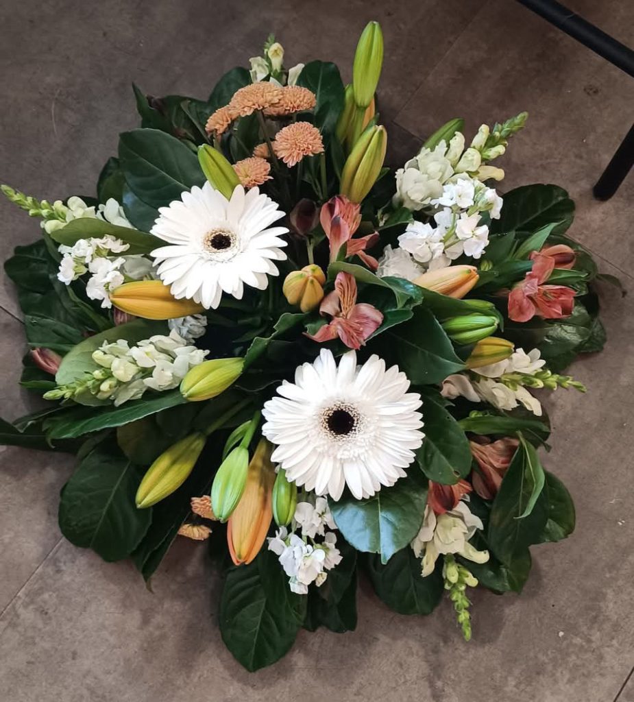 Une composition funéraire pour un deuil dans les tons blancs et oranges avec des fleurs de lys