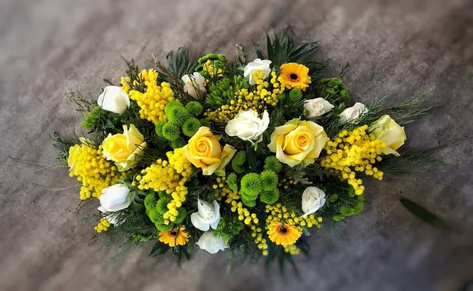 Une gerbe de fleurs pour un deuil dans les tons jaunes avec des roses et du mimosa