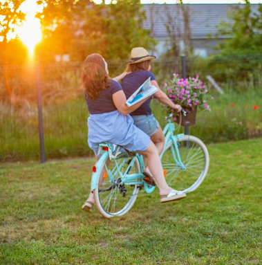 Les deux fleuristes sont dans l'herbe sur un vélo bleu avec des fleurs placées dans le panier au niveau du guidon