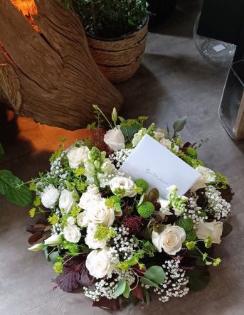 Une gerbe de fleurs réalisée pour un deuil, composée de roses blanche, gypsophile et feuillage vert