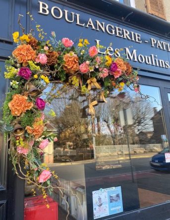 Photo d'une décoration florale dans les tons oranges et roses sur la vitrine d'une boulangerie