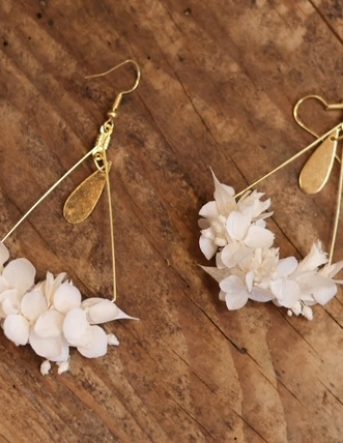 De jolies boucles d'oreille dorées crées à la main avec de petites fleurs blanches séchées