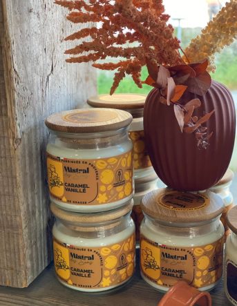 Les bougies artisanales Mistral des Sens au caramel et à la vanille posées à coté d'un vase de fleurs séchées