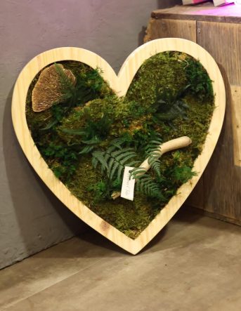 Un cadre végétal en forme de coeur, composé de fougère et de mousse