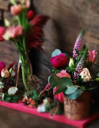 Une composition sur-mesure avec des fleurs roses et violettes sur fond en bois foncé