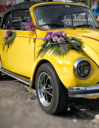 Une voiture coccinelle jaune décorée de fleurs par les fleuristes Un Brin d'Folie pour un mariage dans les Vosges